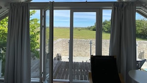 A room with a large glass door leading to an outdoor area, a wooden deck, and a table with chairs. - 4 Person Holiday Home in Morbylanga (Morbylanga)