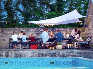 An outdoor seating area with stone walls, string lights, and a pool. - 4 Person Holiday Home in Morbylanga (Morbylanga)