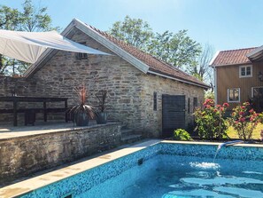 A stone building with a tiled swimming pool, a wooden deck, and potted plants. - 4 Person Holiday Home in Morbylanga (Morbylanga)