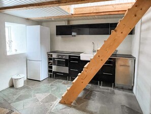 Eine kompakte Küche mit Kühlschrank, Herd, Spüle und Schränken.