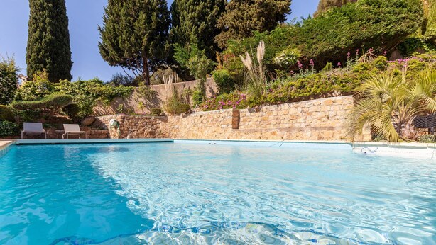 Piscina com água cristalina, rodeada por paredes de pedra e vegetação exuberante.