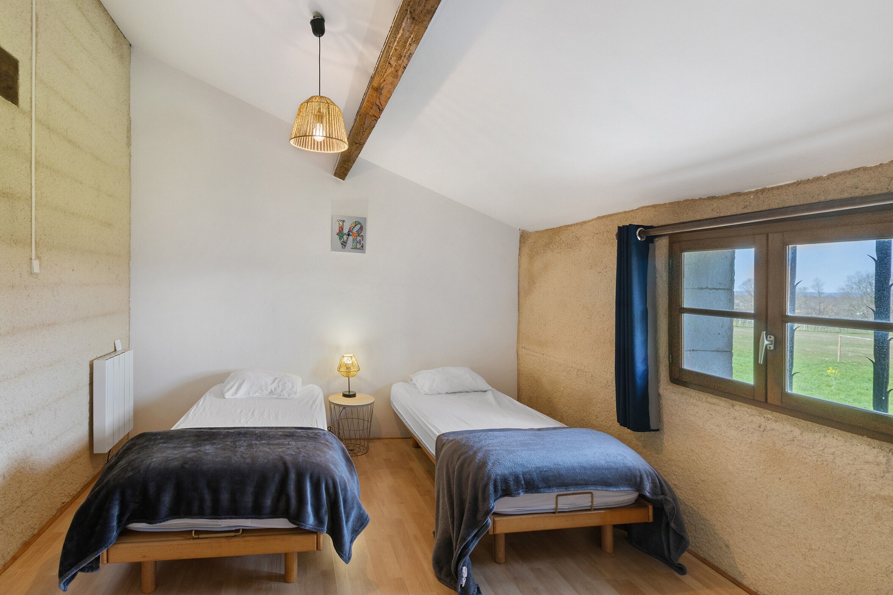 A bedroom with two beds, a window, a lamp, and a radiator.