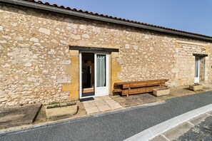 A stone building with a sign 'HARRIET' above the entrance, a bench outside, and a paved street in front.