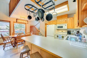 A kitchen with wooden cabinets, a white countertop, and hanging pots. - Wake up to Lake Pend Oreille views, soak in the private hot tub, and paddle out from your dock. This lakefront Bayview cabin sleeps 10 with two decks, paddle boards, fire pit, barbeque, and covered boat slip. A unique family getaway in North Idaho! (Bayview)