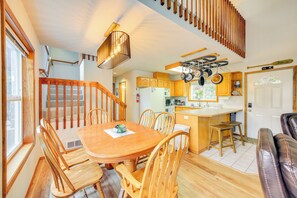 A spacious kitchen with wooden cabinets, a dining area with a wooden table and chairs, and a staircase leading to an upper level. - Wake up to Lake Pend Oreille views, soak in the private hot tub, and paddle out from your dock. This lakefront Bayview cabin sleeps 10 with two decks, paddle boards, fire pit, barbeque, and covered boat slip. A unique family getaway in North Idaho! (Bayview)