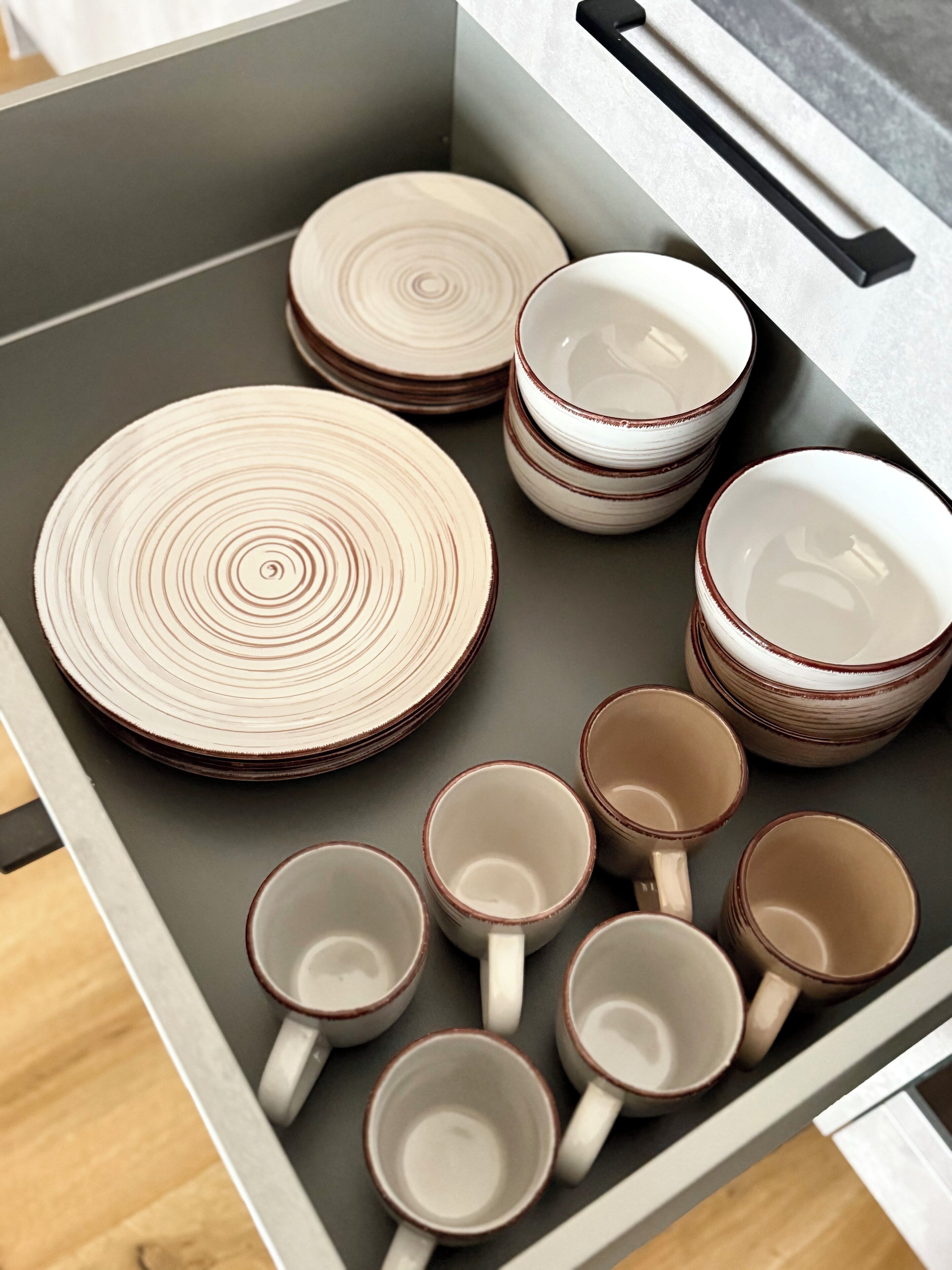 A drawer containing neatly stacked plates and cups.