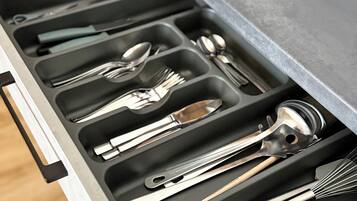A kitchen drawer with utensils organized in compartments.