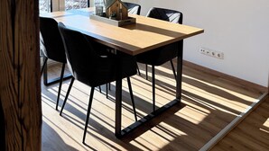 Un comedor con una mesa de madera, sillas negras y vistas al exterior a través de grandes ventanales.