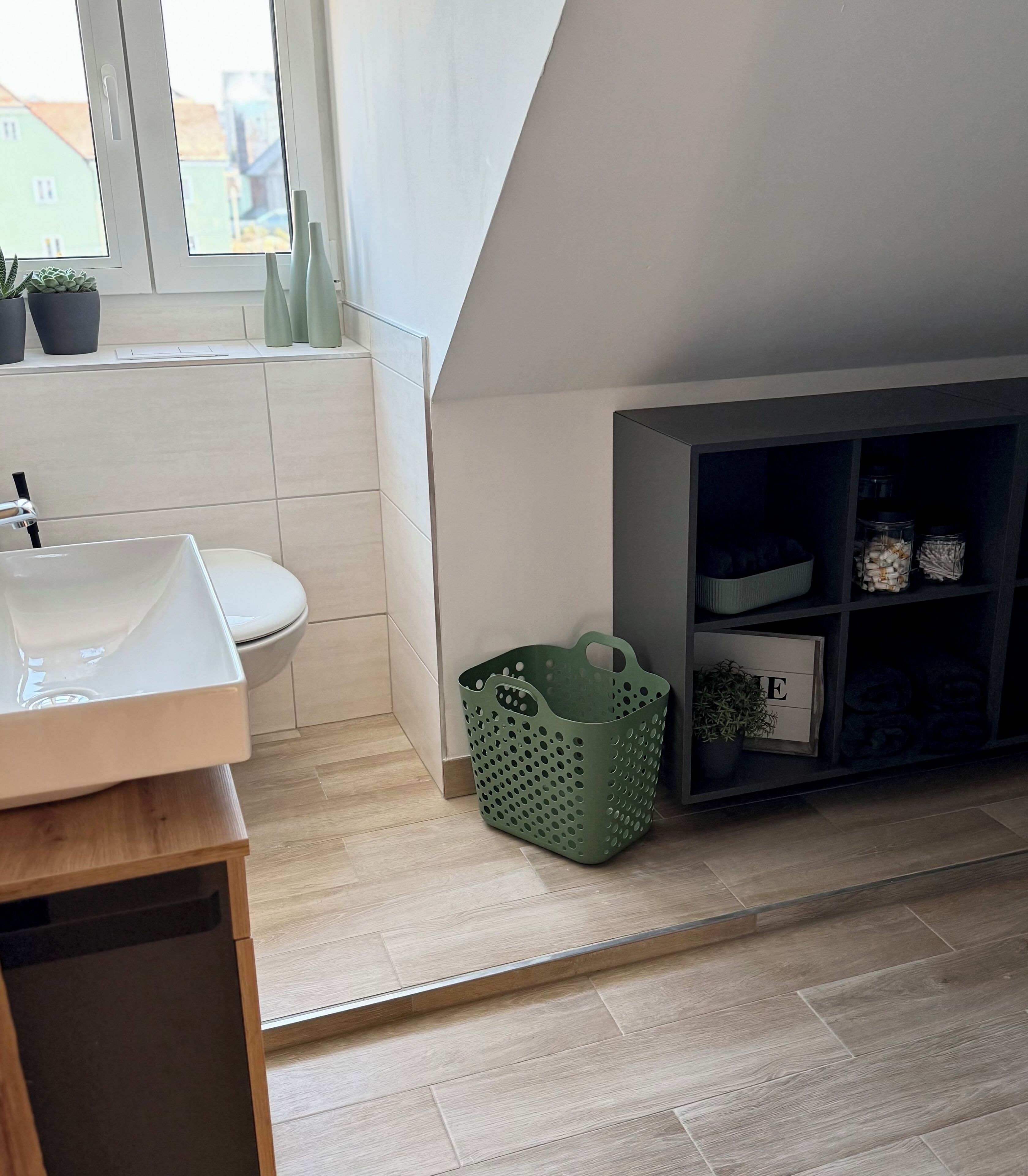 Ein modernes Badezimmer mit Toilette, Waschbecken und einem grünen Korb auf dem Boden.