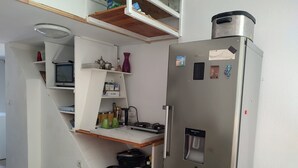 Una cucina compatta con frigorifero integrato, forno a microonde e un piccolo lavandino.
