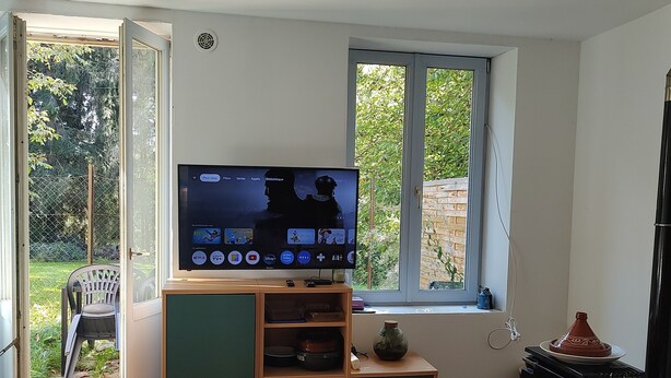 Una stanza con televisione, mobili in legno, un tavolino e una finestra.