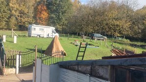 Un'area recintata con un edificio bianco, un prato e un camper sullo sfondo.