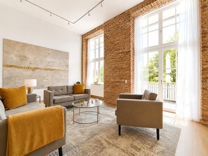 Ein geräumiges Wohnzimmer mit einer großen Ziegelwand, einem modernen Sofa, einem Couchtisch und einem großen Fenster mit Blick ins Grüne.