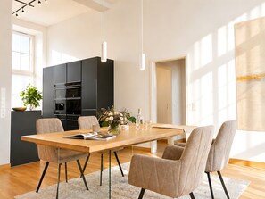 Eine moderne Küche mit schwarzen Schränken, einem Holztisch und beigen Stühlen.