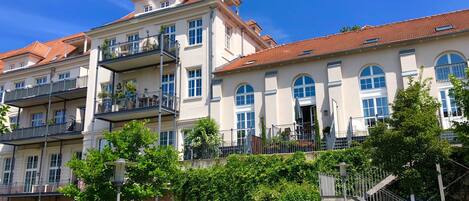 A multi-story hotel with balconies, a central staircase, and lush greenery.