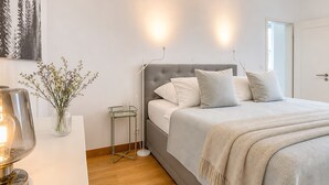 A bedroom with a bed, bedside table, lamp, and wall-mounted light. - Apartment '4 Neue Suite, 79qm' with Shared Terrace, Balcony and Wi-Fi (Baden-Baden)