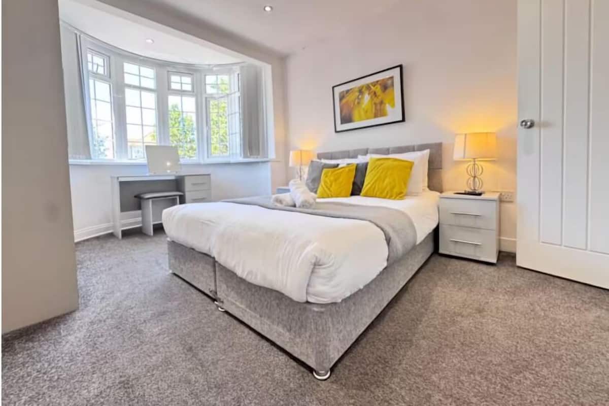 A bedroom with a large bed, a desk, and a window.