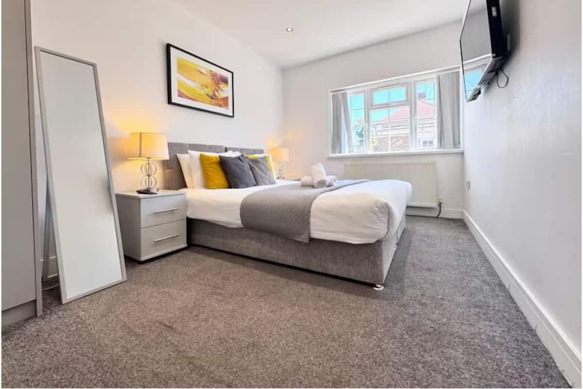 A modern bedroom with a bed, bedside tables, a window, and a painting on the wall.