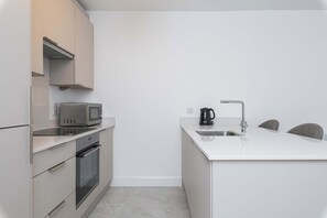 Eine moderne Küche mit Edelstahlgeräten, einer eingebauten Mikrowelle, einem Wasserkocher und einem Spülbecken.