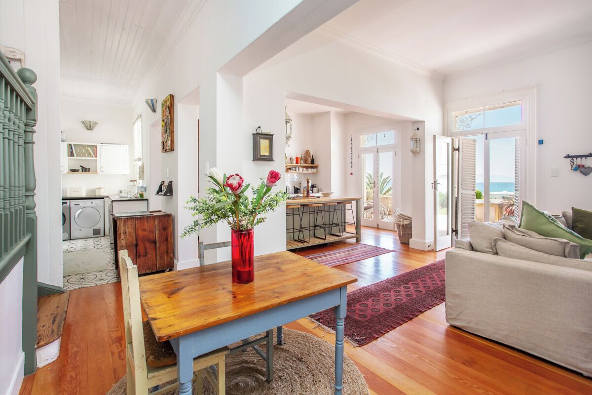 A spacious living area with a wooden dining table, a sofa, and a view of the kitchen and dining area.