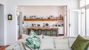 A cozy living room with a sofa and a kitchen in the background.