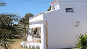 Un bâtiment blanc avec un toit plat, une petite fenêtre et un lampadaire.