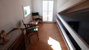 Une pièce étroite avec une cheminée, une petite table et deux chaises.