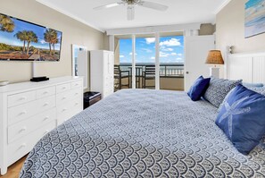 A bedroom with a bed, a dresser, a television, a ceiling fan, a lamp, and a view of the beach. - 2BR Top-Floor Oceanfront Condo with Beach & Pool View (Pawleys Island)