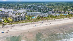 Ett hotell vid kusten med flera byggnader, en sandstrand och en sjö i bakgrunden.