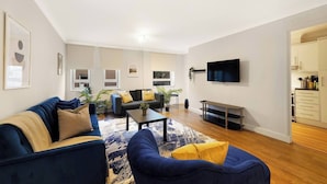 A modern living room with a sofa, coffee table, and a TV mounted on the wall. - Lux 3-Bed 3-Bath Apt, Terrace, Underground Parking (London)