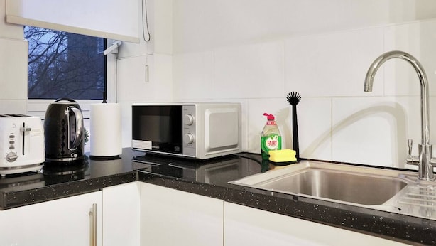 A modern kitchen with a toaster, kettle, microwave, and a sink with a faucet. - Lux 3-Bed 3-Bath Apt, Terrace, Underground Parking (London)