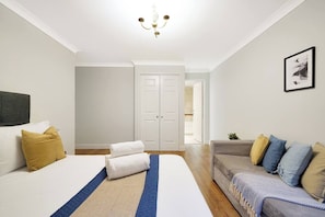 A hotel room with a bed, a sofa, a door, and a chandelier. - Lux 3-Bed 3-Bath Apt, Terrace, Underground Parking (London)