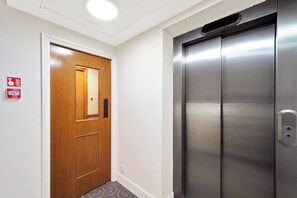 A wooden door with a mirror and a fire alarm sign, and a metallic elevator door. - Lux 3-Bed 3-Bath Apt, Terrace, Underground Parking (London)