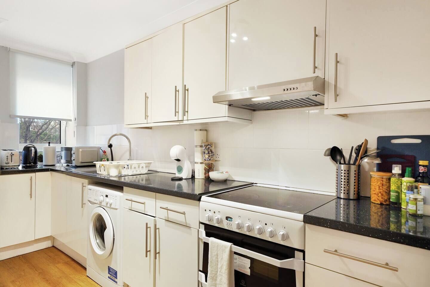 A modern kitchen with a washing machine, oven, and a built-in microwave.