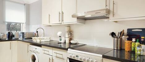 A modern kitchen with a washing machine, oven, and a built-in microwave.