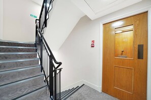 Un escalier avec une rampe noire menant à une porte en bois portant le numéro 45.