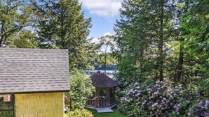 Ett hus med en liten trädgård, en lusthus och en sjö i bakgrunden.