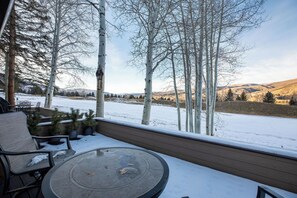 Un espacio de estar al aire libre techado, con vistas a un paisaje nevado y árboles.