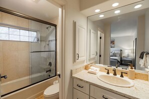 Un baño moderno con ducha de vidrio, un lavabo blanco y un espejo grande.
