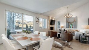 Uma sala de estar moderna com lareira, um chifre de veado na parede e uma grande janela com vista para uma paisagem coberta de neve.