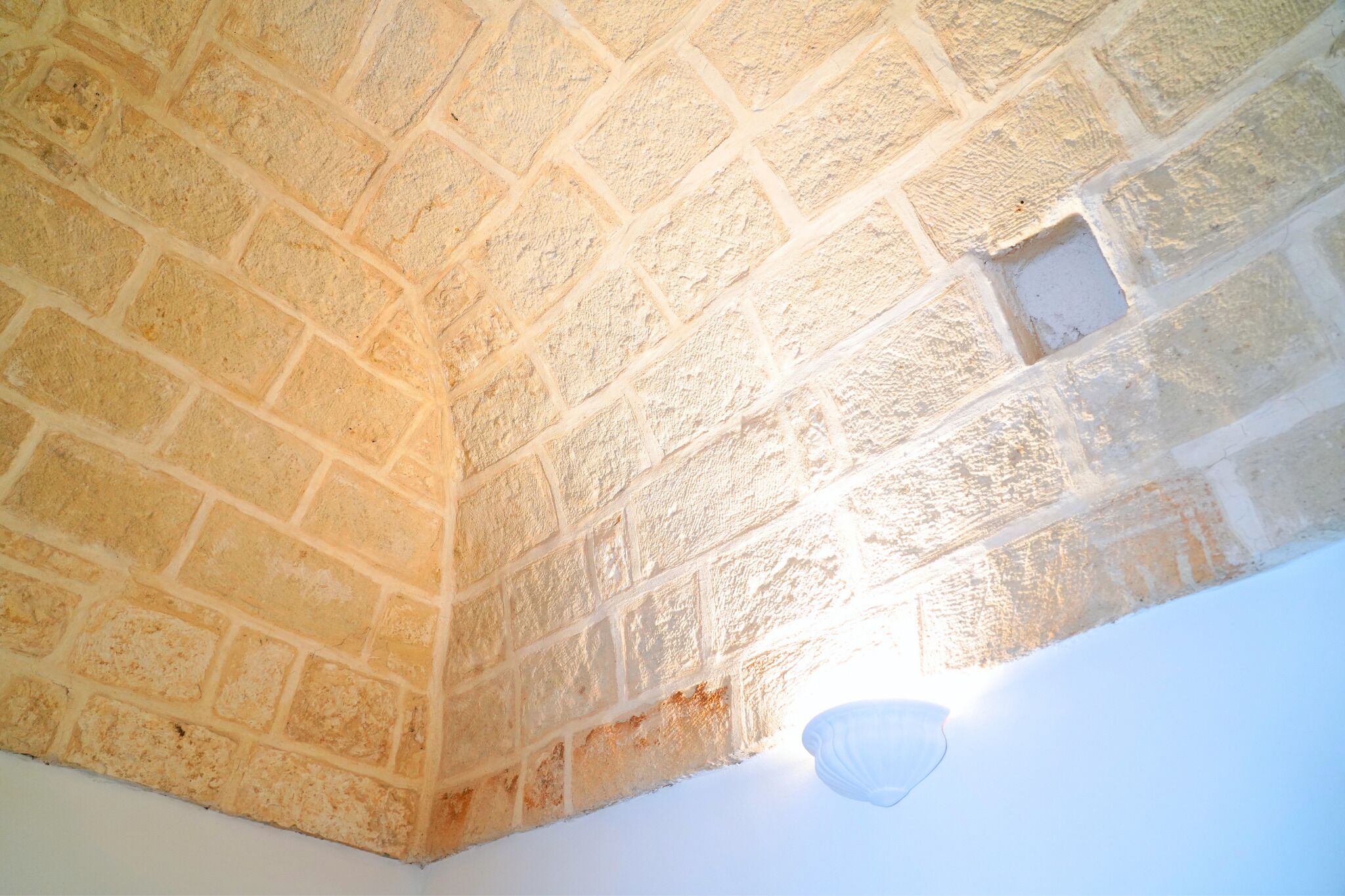 A stone wall with a recessed area and a light fixture.