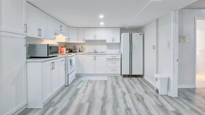 A modern kitchen with white cabinetry, a microwave, a refrigerator, and a sink. - A Very Peaceful Home (Oshawa)