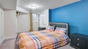 A bedroom with a bed, nightstands, a dresser, and a window with curtains. - A Very Peaceful Home (Oshawa)
