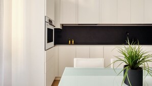 A modern kitchen with white cabinets, a black countertop, and a potted plant. - Hostmate - Milano - Donatello - Città Studi (Milano)
