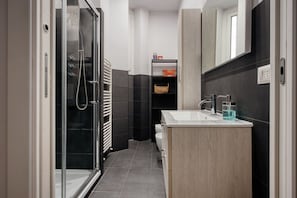 Ein modernes Badezimmer mit Duschkabine aus Glas, einem weißen Waschbecken und einem Holzausleger.
