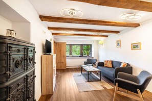 Una sala de estar con sofá, sillones, una mesita de centro, televisor y chimenea.