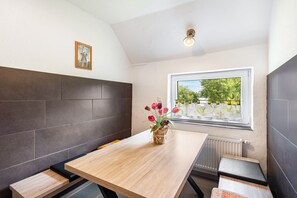 Una cocina moderna con una mesa de madera, un florero y una ventana con vistas a zonas verdes.