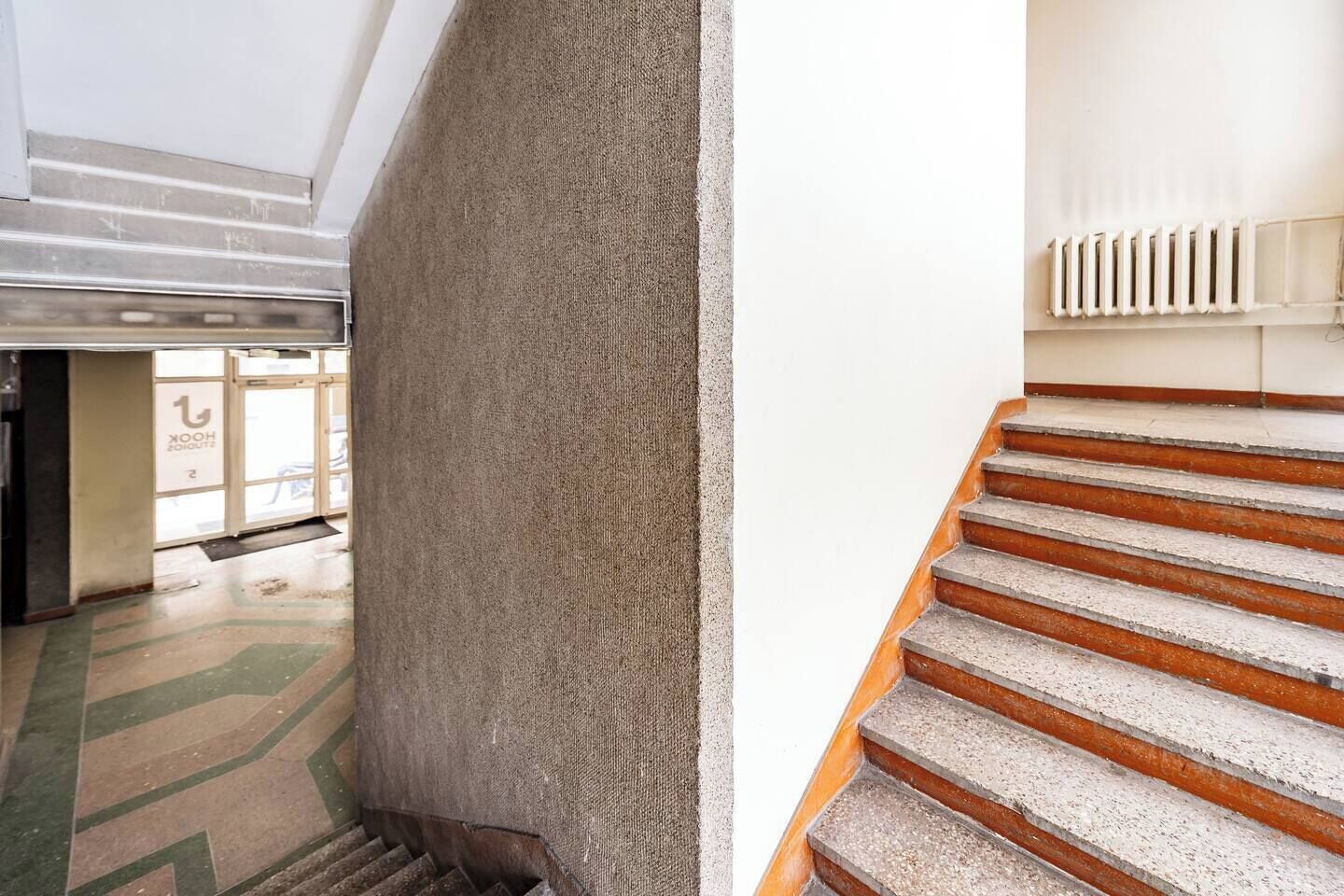 A staircase with a handrail and a radiator above it.