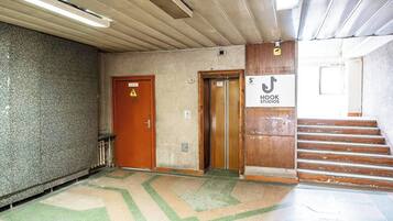 A hallway with a wooden door, an elevator, and a staircase leading to a room marked '5th floor Hook Studios'.
