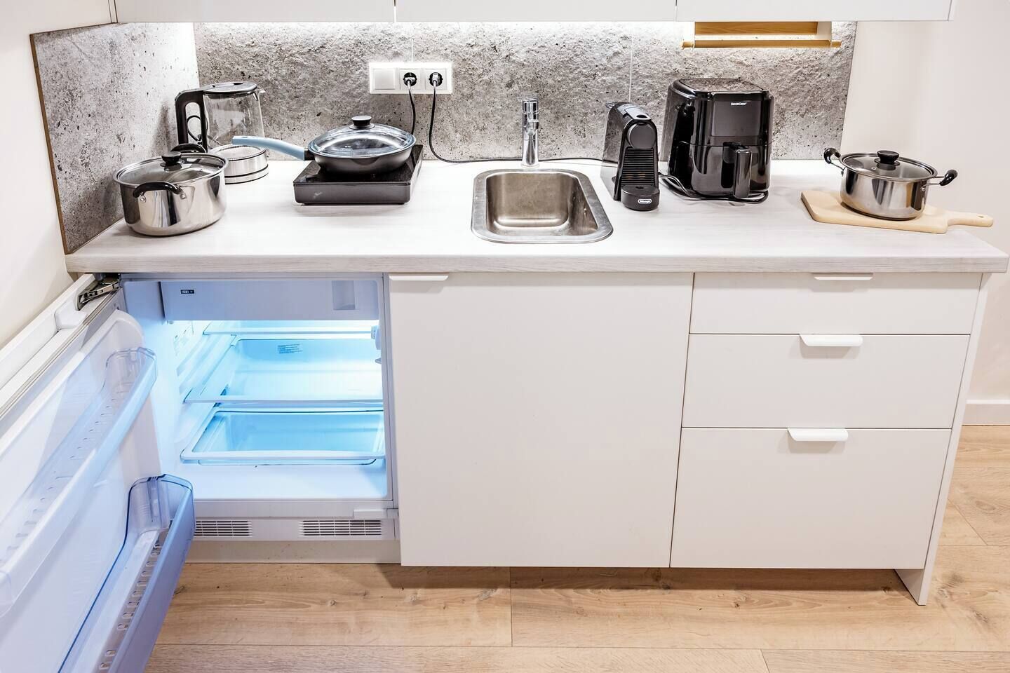 A kitchen with a built-in refrigerator, a sink, and various appliances like a coffee maker and a kettle.